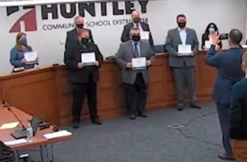 In a photograph that could be a sign of the COVID-19 age, District 158 school board members, all wearing masks, stand social distance apart for a photograph with certificates of appreciation signifying School Board Appreciation Week.