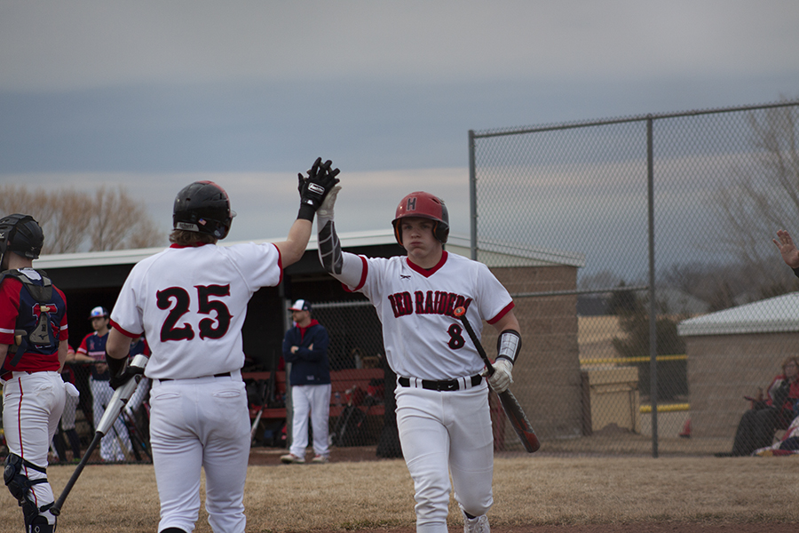 Ryan Kelly, left and Brayden Bakes, high-five each other during a game against Belvidere North March 17. The Red Raiders won the home opener, 9-4.