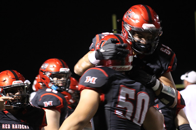 Huntley senior Kaden Buchholz (64) congratulates classmate Ben Wiley after Wiley's 32-yard fumble recovery for a touchdown against McHenry. The Red Raiders outlasted the Warriors, 23-15, Sept. 2.