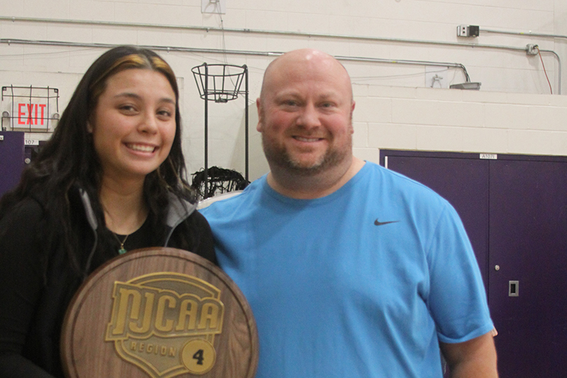 MCC Vollleyball player Dana Devera, left and head coach Kyle McCall with a NJCAA Region IV trophy.