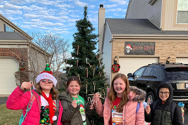 Visitors stop by to take their candy canes from the Holiday Habits outdoor candy cane tree.