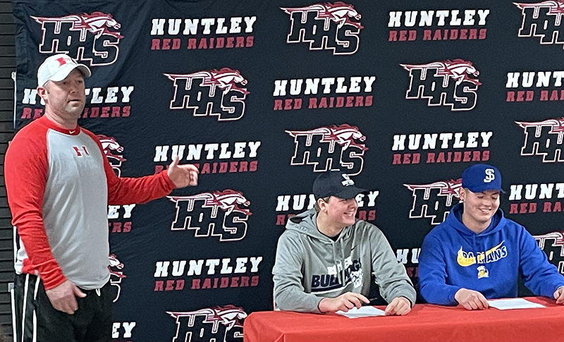 Huntley head football coach Mike Naymola, congratulates seniors Eric Bower and Luke Griskey on signing national letters of intent.