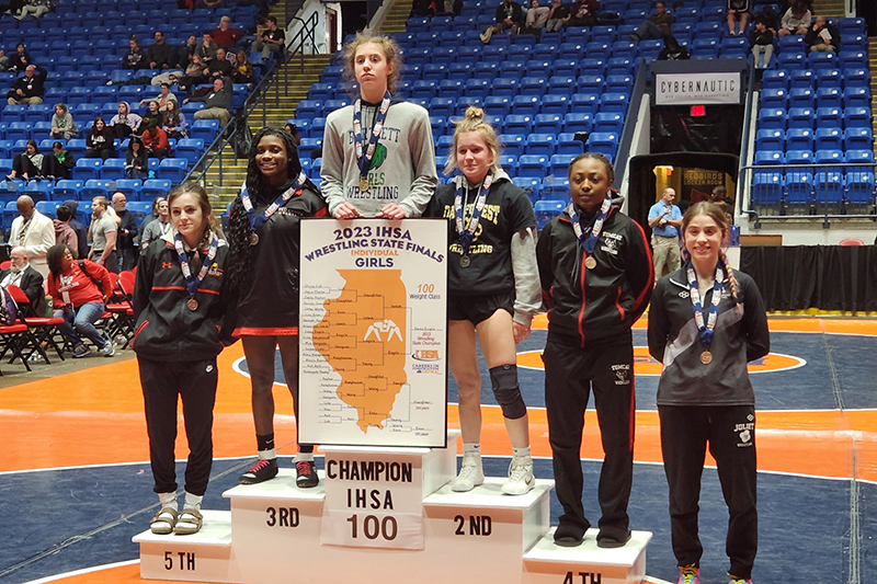 Huntley freshman Jeniah Slaughter, second from left, stands on the podium after earning a third place medal competing at 100 pounds at the IHSA Girls State Wrestling Tournament.