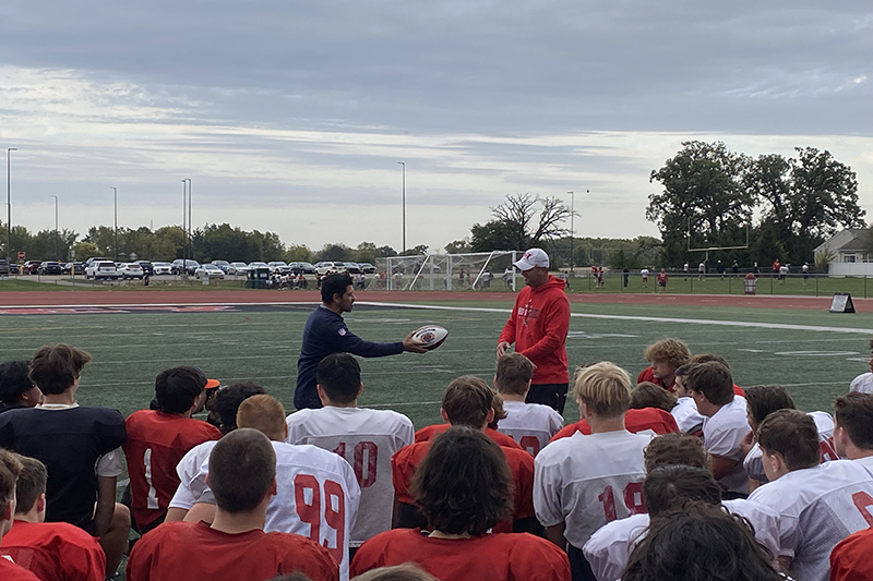 Huntley High School players look on as a Chicago Bears representative presents head coach Mike Naymola with the team's High School Coach of the Week award.