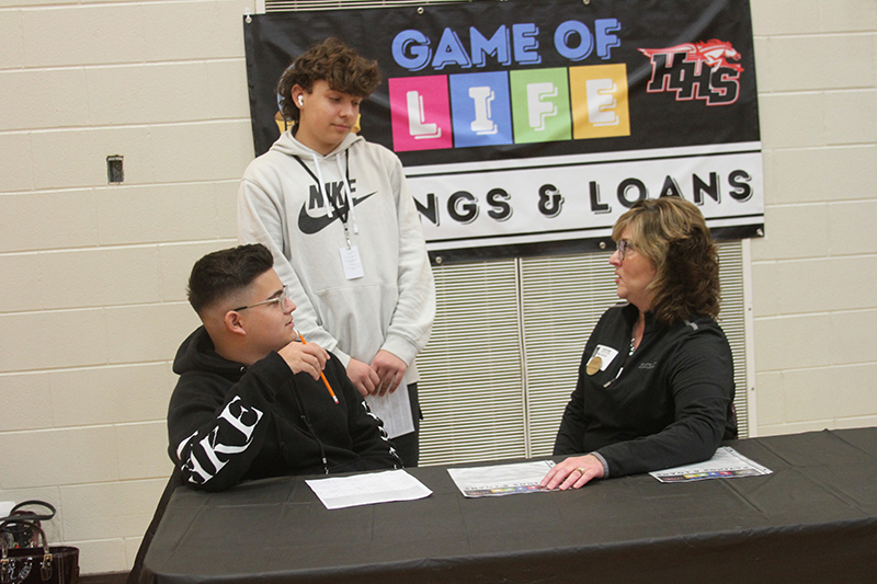 Huntley High School sophomores Ashton Figgieri, left and Pawel Krystopa meet with Mary C. Caporale, vice president retail banking manager at Algonquin Bank & Trust, during the Game of Life event at Huntley High School.