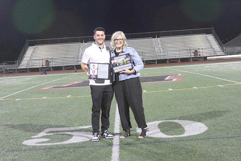 Huntley alumnus Anthony Binetti, left and Kim Popenfoose, representing the Popenfoose family, show plaques at the Huntley Football Hall of Fame ceremony.