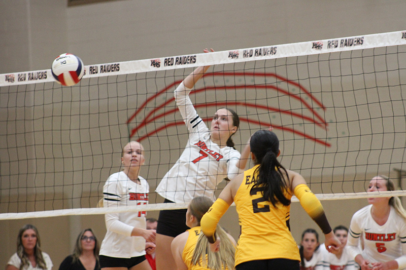 Huntley senior Jocelyn Erling sends a kill over the net against Jacobs.Teammates Julia Lesniak (14) and Emily Ernst look on.