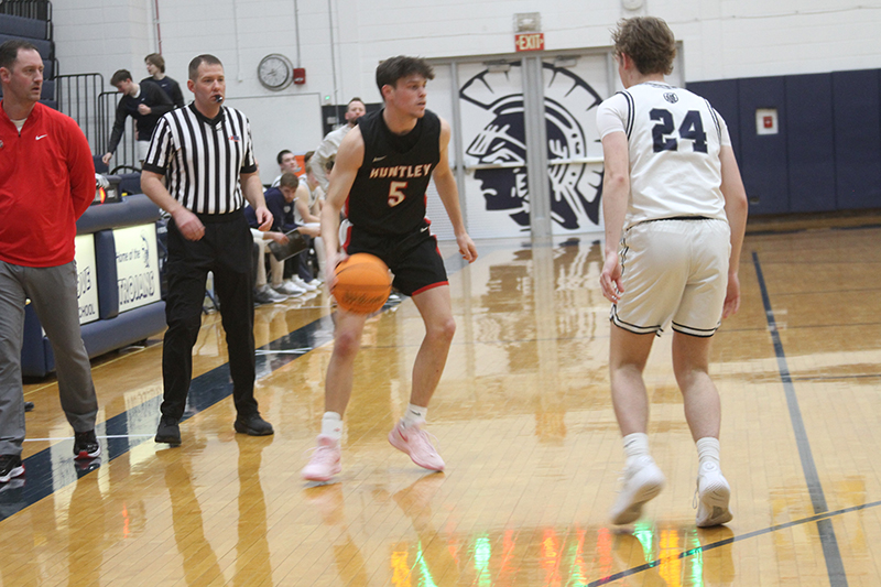 Huntley senior Zach Rysavy starts a play against Cary-Grove. Red Raiders coach Collin Kalamatas looks on.