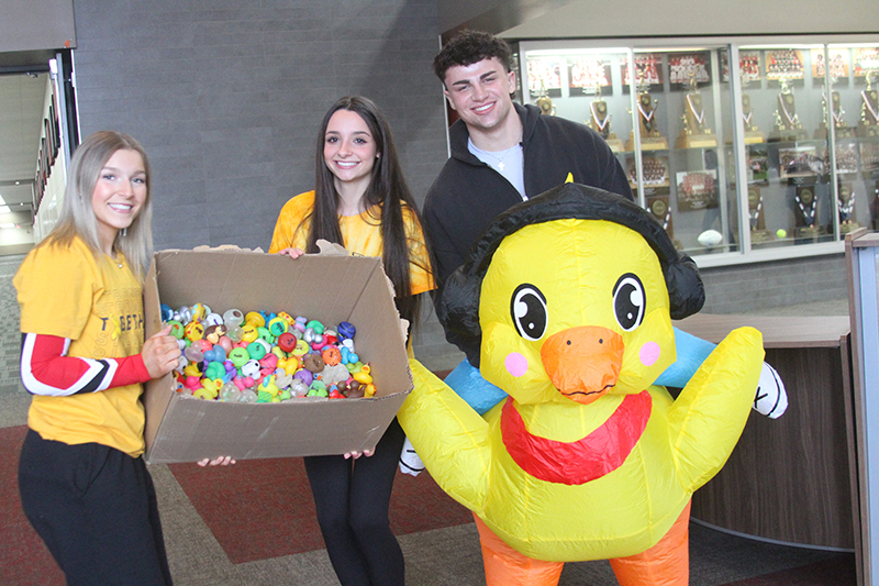 Huntley High School Raider Nation leaders Abby Rosa, Brooke Rogers and Drew Donovon encourage fans to buy “Chuck-A-Duck” chances at the Feb. 14 event.